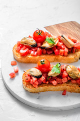Smoked mussels on grilled bruschetta with tomatoes, white background, isolated