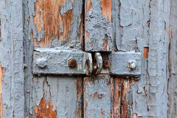 old wooden door with brackets for padlock and with peeling paint