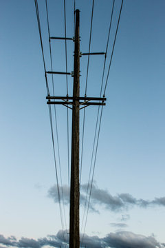 Electricity runs through power lines on a power pole at twilight