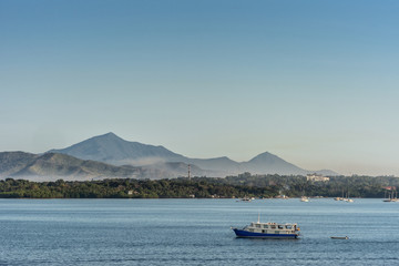 Puerto Princesa, Palawan, Philippines - March 3, 2019: The bay in front of the city shows blue water and brown mountains coverd in a light haze in the distance. Pleasure boats. Light blue sky.