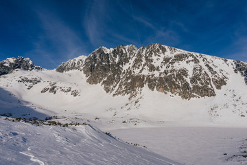 Obraz premium Winter view of the highest mountain of Slovakia and High Tatras, Gerlach mountain. Gerlachovsky stit in winter. High alpine mountain landscape covered with snow and ice. Blue vibrant sky.