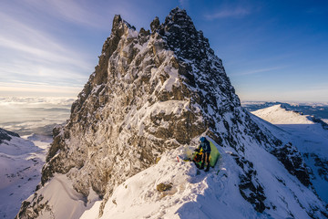 An epic panorama view of a mountainer or climber and his tent in a winter alpine mountain...