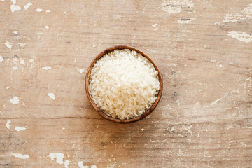 White rice in wooden bowl on wood background