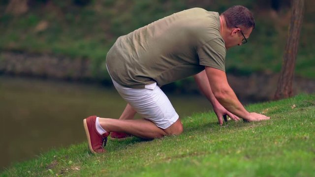 Man searching the grassy bank of a pond