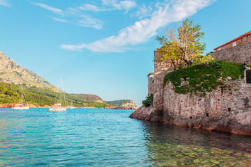 Fototapeta na wymiar Picturesque summer seascape, part of Sveti Stefan island and luxury yachts in adriatic sea, Montenegro