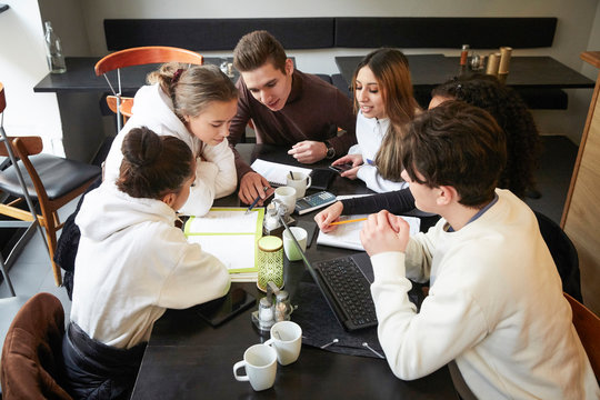 Male and female friends studying at table in cafe