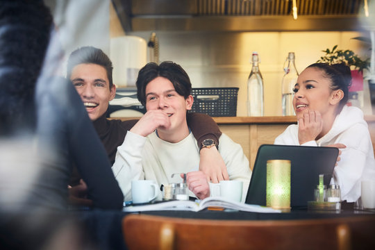 Smiling male and female teenage friends sitting at table in restaurant