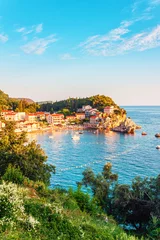Picturesque summer view of Adriatic sea coast in Budva Riviera. Przno village with buildings on the rock at sunset warm sunlight, Montenegro