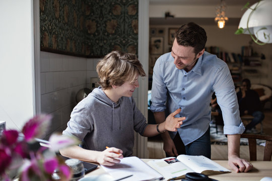 Smiling son thanking father for his help in doing homework at home