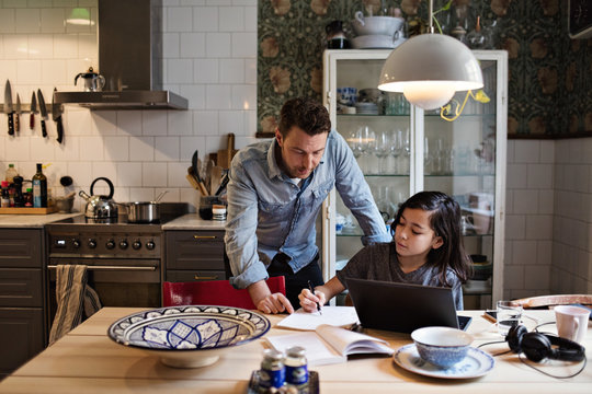 Father guiding son in doing homework at home