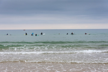 View from the beach of a group of surfers waiting for the waves, a cloudy afternoon in Cantabria,...