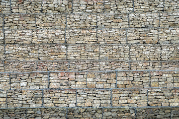 Gabion Wall From Rocks And Stones In Metal Wire Box. Fence of stones in the grid. Protective stone wall in the grid.