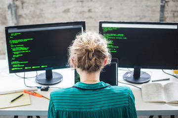 High angle view of female IT expert working on computer programs at desk in creative office