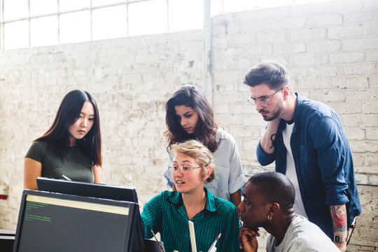 Young female entrepreneur having discussion over computer codes with hackers in office