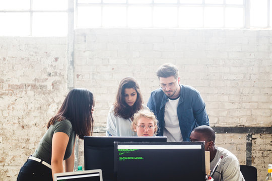 Serious IT experts using desktop PC while coding computer programs in office