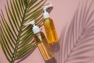 Fototapeta premium Natural cosmetic oil in a clear bottle with tropical leaf and shadow