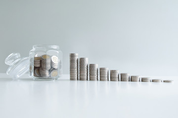 coin in glass bottle bank with coins bar graph, step up growing business to success and saving for retirement concept