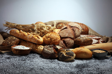 Assortment of baked bread and bread rolls on rustic grey bakery table background
