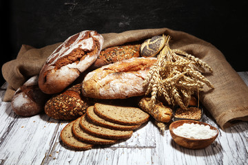 Assortment of baked bread and bread rolls on rustic white bakery table background