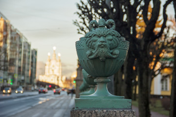 Fototapeta premium Maskaron from the fence of the Tauride Palace (in which the Inter-Parliamentary Assembly of the CIS member states is located) against the background of the Smolny Cathedral