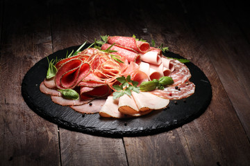 Food tray with delicious salami, pieces of sliced ham, sausages,salad and vegetable. Meat platter...
