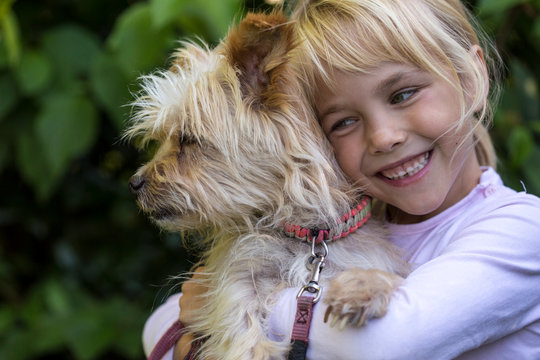 Portrait Of Happy Little Girl Cuddling Her Dog