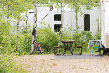 a camping site pictures in deep woods with modern camping equipment like tents, RV, picnic benches