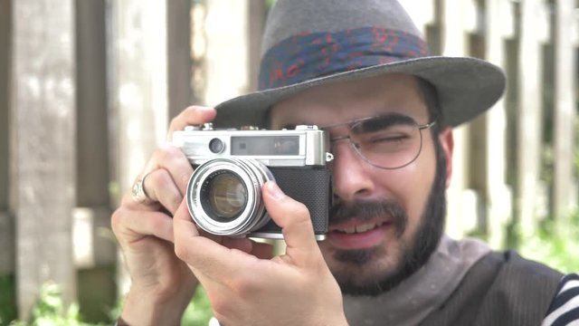 Millennial hipster using an old 35mm film camera outdoors