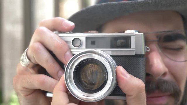 Millennial hipster using an old 35mm film camera outdoors