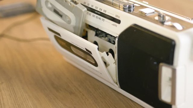 Using a boom box cassette player by inserting a tape to listen to music.