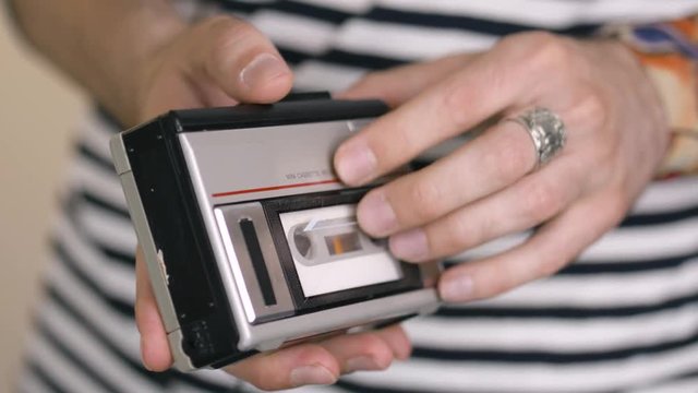 Using a portable cassette player by inserting a tape to listen to music.