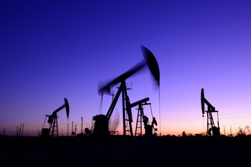 The pumping unit is working, silhouetted against the setting sun