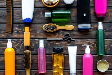 Fototapeta premium Cosmetics for hair with oil, scissors, comb, conditioner and shampoo in bottle on wooden background top view pattern