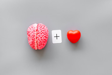 feelings and mind concept with brain plus heart on gray background top view