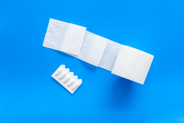 Toilet paper roll and rectal suppository for proctology diseases concept on blue background top view