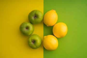 Green apple and lemon on green and yellow paper background