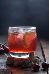 cherry and lime cocktail on a wooden floor with garnish