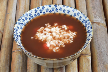 Sweet rice dumplings in fermented rice soup on bamboo table