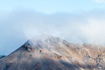 Landscape view of Laugarvatn mountains with clouds covering wrapping cliffs at Golden circle in Iceland with blue color sky in autumn