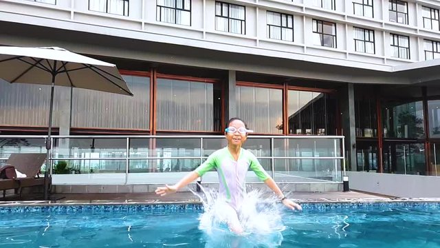 Slow motion of little girl jumping into the swimming pool while wearing swimwear