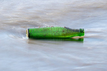 Long exposure of a forlorn green bottle washed up on the shore