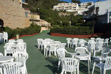 Many white plastic chairs on a green background.