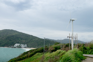 Seascape of Promthem cape with Wind Turbine arespinning  on the hillside by the beach.