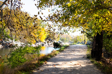 Empty trail path during autumn Potomac river in Great Falls, Maryland with colorful foliage and...