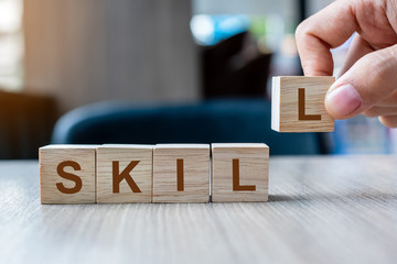 Businessman hand holding wooden cube block with SKILL business word on table background. Ability, Learn, Knowledge, Technical, Professional and Experience concepts