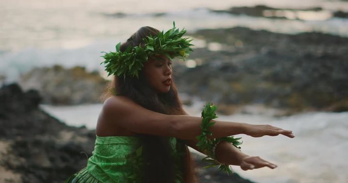 Traditional Hawaiian hula dancing at sunset in slow motion, woman performing Hawaiian hula with haku leis and ti leaf skirt