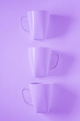3 purple coffee mugs on purplish background in a vertical row, empty copy space