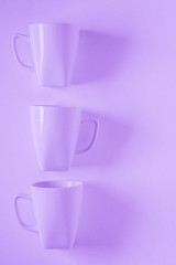 3 purple coffee mugs on purplish background in a vertical row, empty copy space