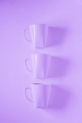 3 purple coffee mugs on purplish background in a vertical row, empty copy space