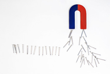 magnet in the form of a horseshoe pulling all the nails on white background